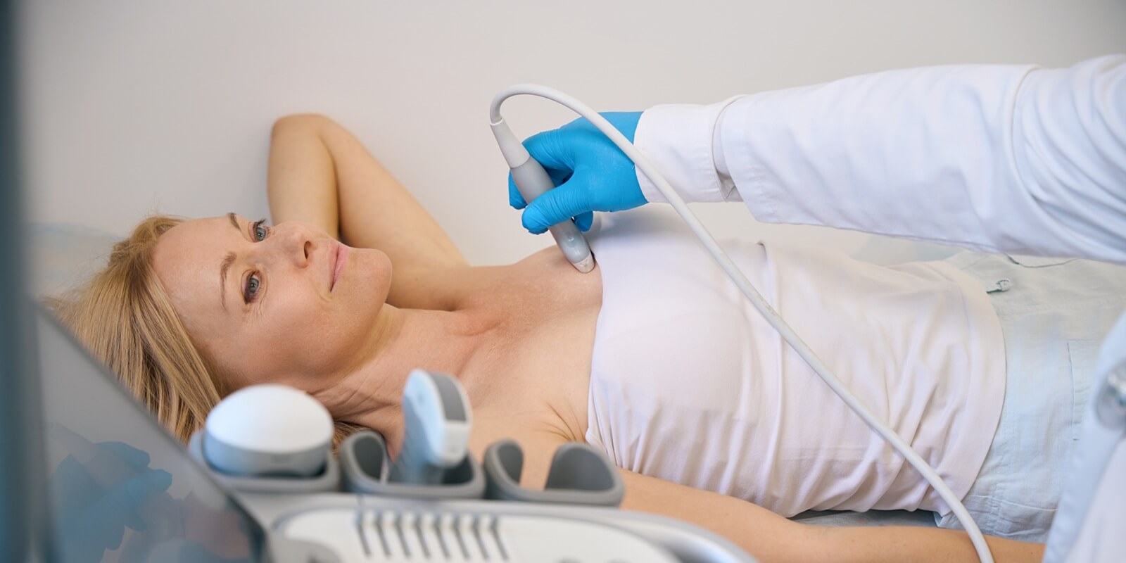 female getting her breast examined by doctor at modern clinic