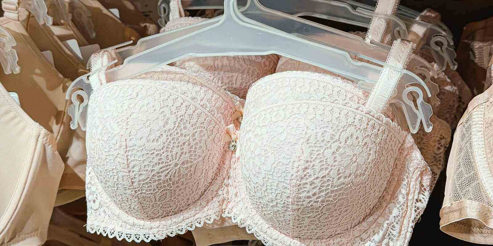 multiple light pink lace bras hanging in a clothing store