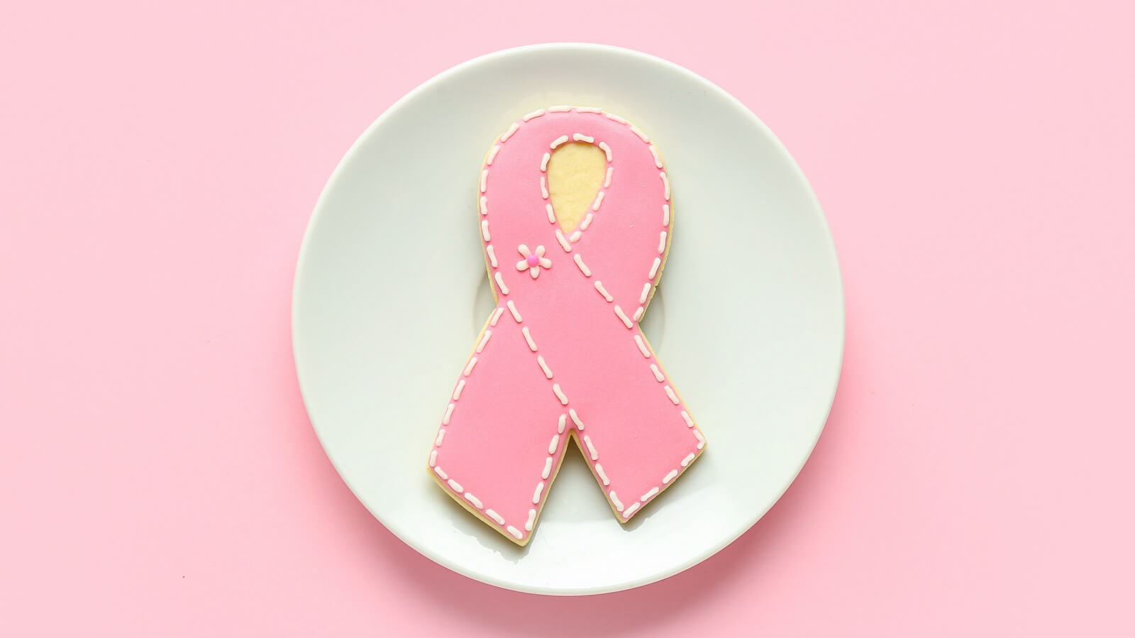 breast cancer screening - plate with cookies in shape of pink ribbon on color background