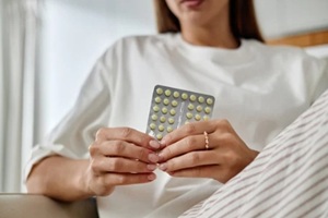 young adult caucasian woman holding blister pack of oral contraceptive pills with both hands