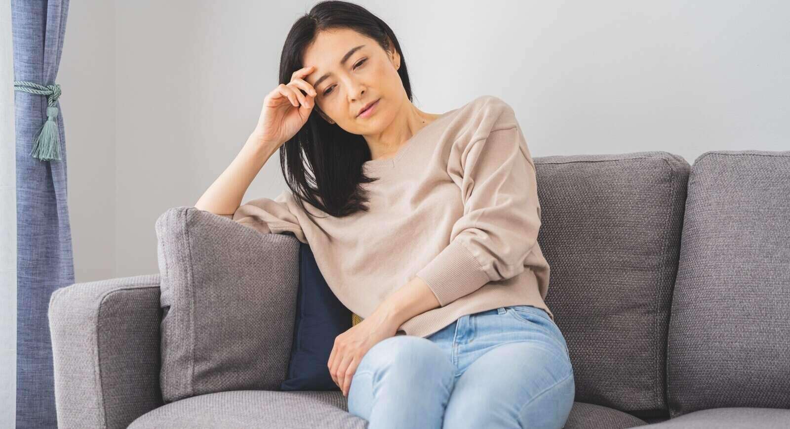 asian women sitting upset on a sofa