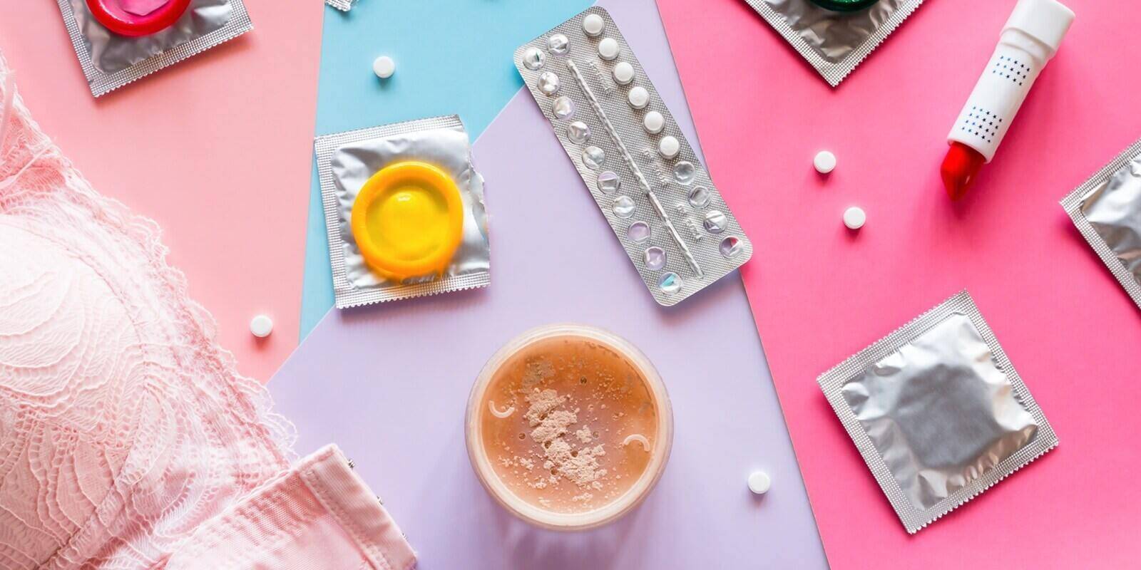 cosmetics, bra, condoms and birth control pills on a colored background